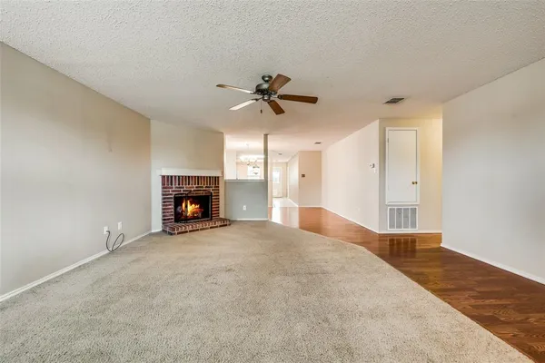 a view of an empty room with a fireplace and a chandelier fan