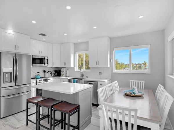 a kitchen with stainless steel appliances granite countertop a dining table chairs and a refrigerator