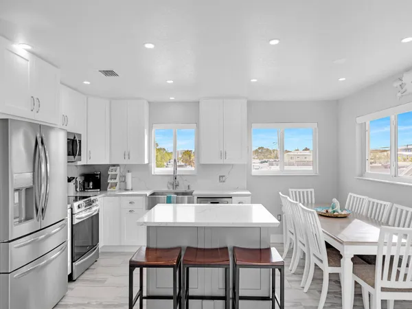 a kitchen with a dining table chairs sink refrigerator and cabinets