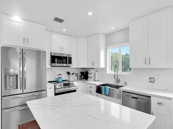 a kitchen with granite countertop a sink stainless steel appliances and cabinets