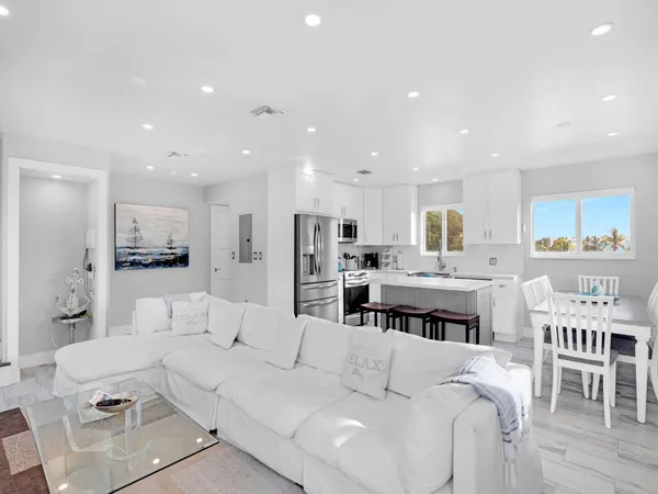 a living room with furniture kitchen area and a table
