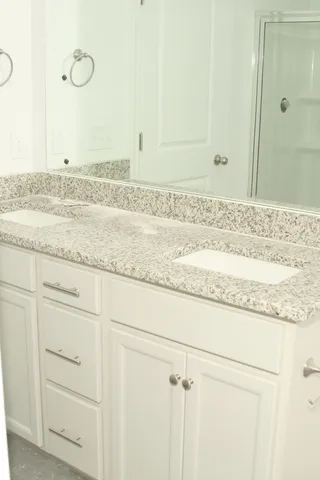 a bathroom with a granite countertop sink and white cabinets