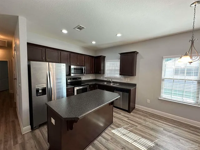 a kitchen with stainless steel appliances granite countertop a sink a stove a refrigerator and cabinets