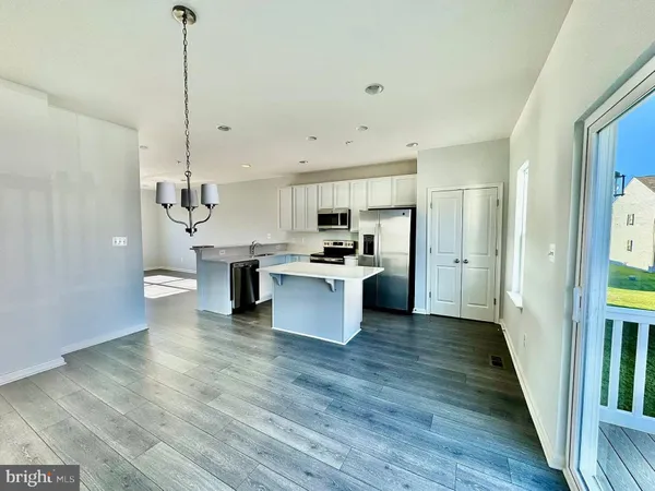 a view of kitchen with kitchen island stainless steel appliances a stove refrigerator and cabinets