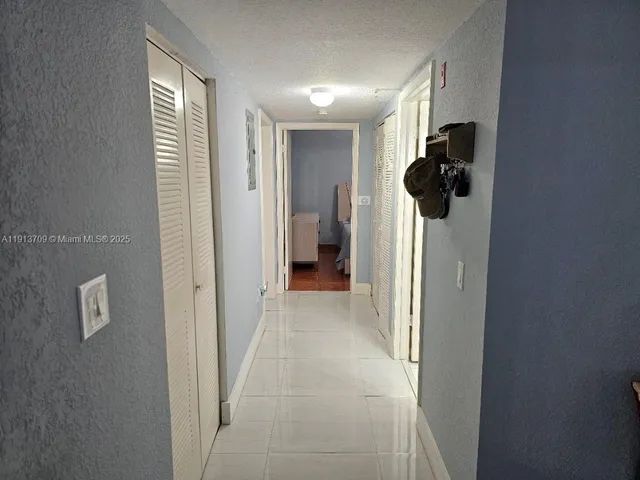 a view of a hallway with wooden floor and a bathroom