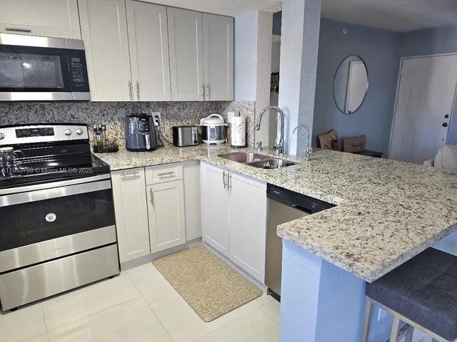 a kitchen with granite countertop a sink a stove and cabinets