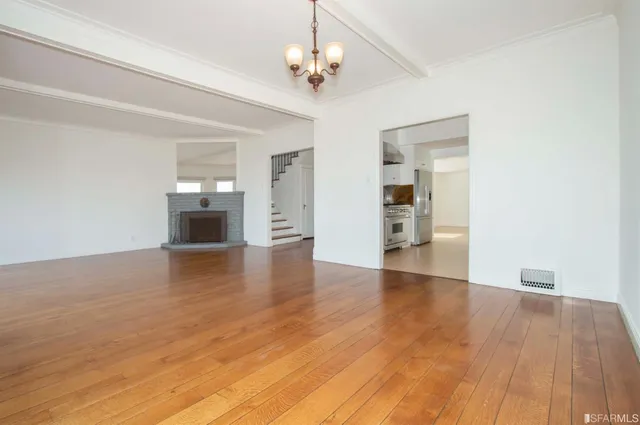 a view of empty room with wooden floor and ceiling fan