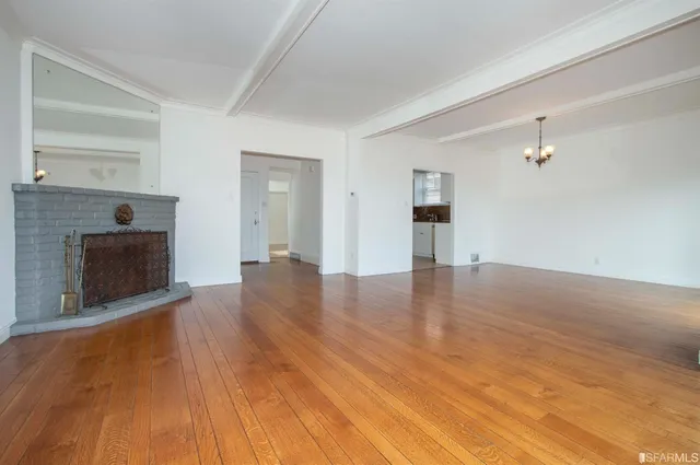 a view of empty room with wooden floor and fireplace
