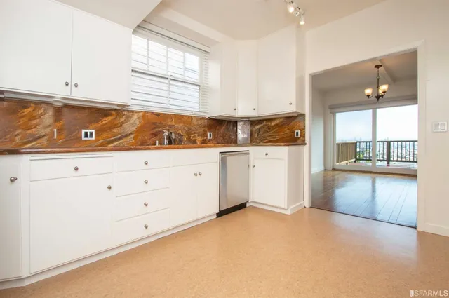 a kitchen with granite countertop white cabinets and window