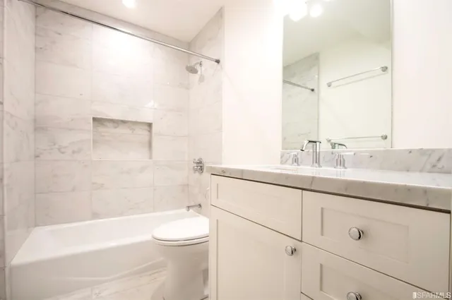 a bathroom with a granite countertop sink a toilet and shower