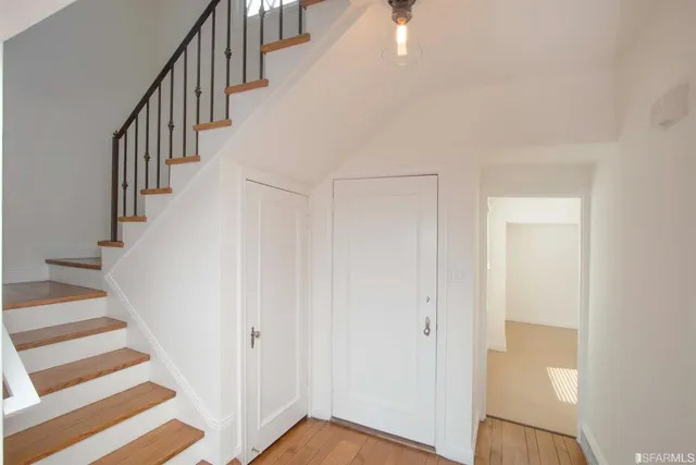 a view of staircase with wooden floor and white walls