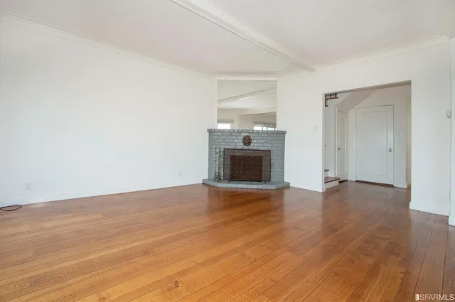 a view of empty room with wooden floor and fireplace