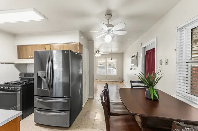 a kitchen with stainless steel appliances granite countertop a refrigerator a stove a sink a dining table and chairs