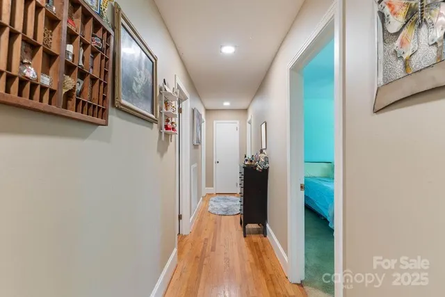 a view of a hallway with wooden floor and a bathroom