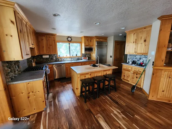 a dining hall with stainless steel appliances granite countertop a stove and a couch