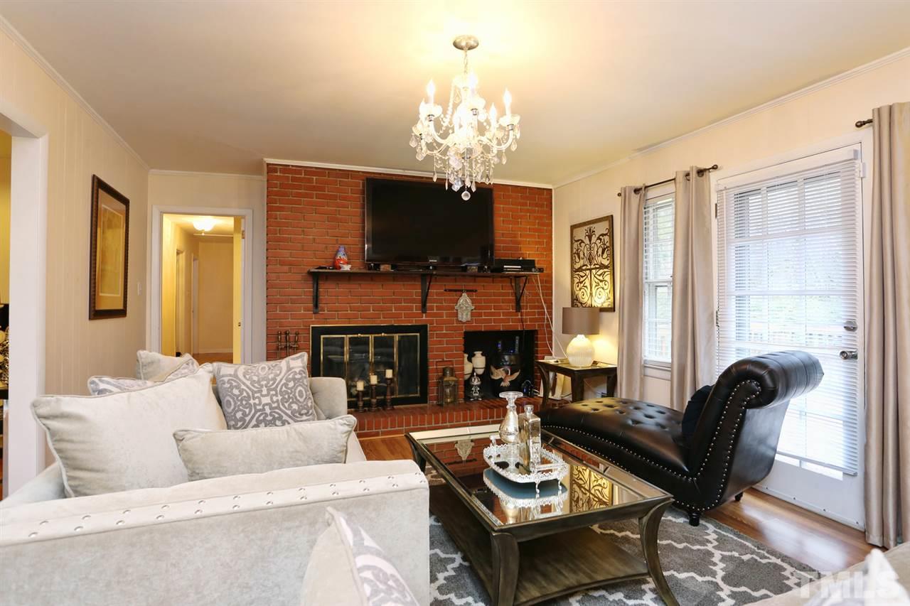 3917 Buffaloe Road Raleigh, NC 27604 - Photo 10 of 24 a living room with furniture a fireplace and a chandelier