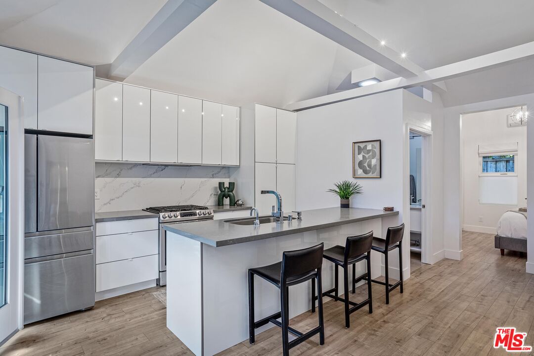 4216 Woodcliff Road Sherman Oaks, CA 91403 - Photo 38 of 56 a kitchen with stainless steel appliances granite countertop a table chairs sink refrigerator and cabinets