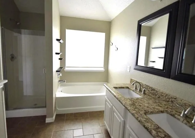 a bathroom with a granite countertop sink and mirror with bathtub