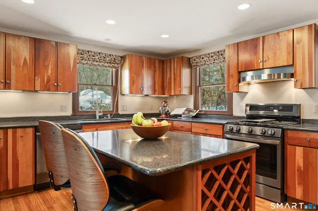 a kitchen with stainless steel appliances granite countertop a sink a stove a table and chairs