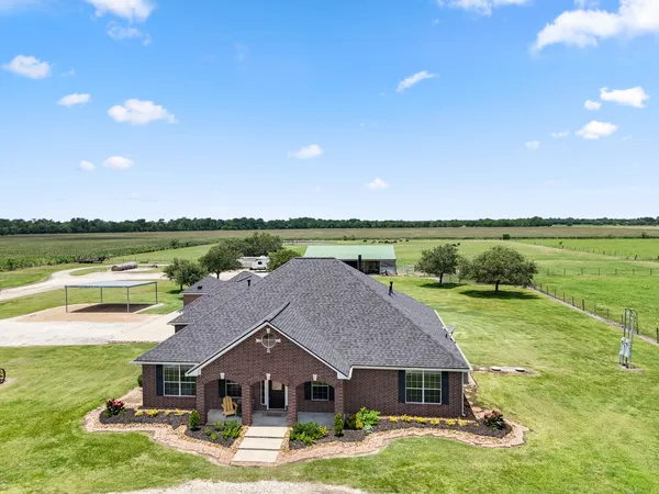 an aerial view of a house with big yard and large trees