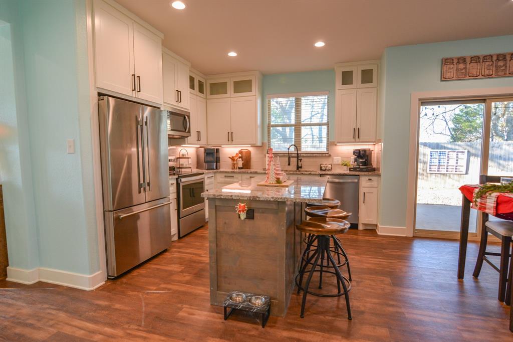601 Mathew Street Grandview, TX 76050 - Photo 9 of 40 a kitchen with stainless steel appliances a refrigerator a stove a sink a dining table and chairs with wooden floor