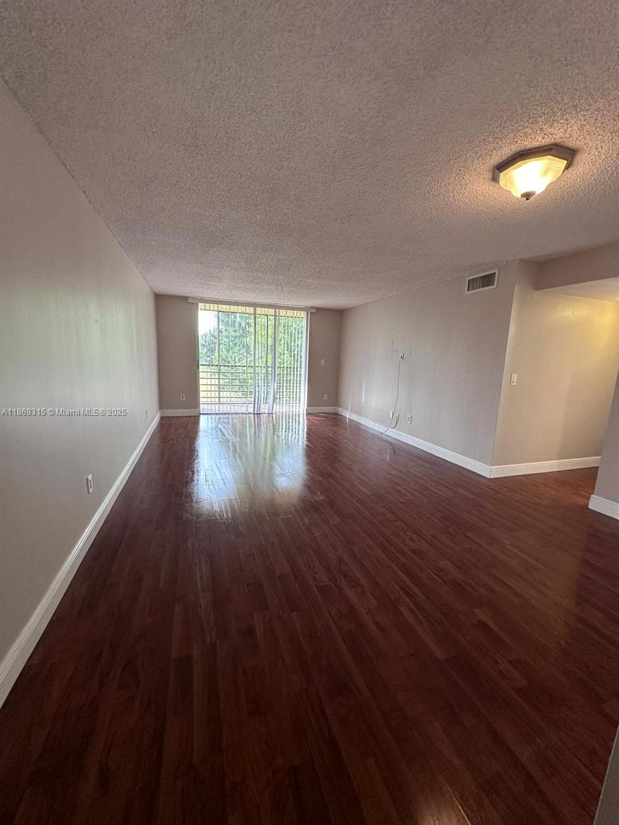 3390 Foxcroft Road, Unit C212 Miramar, FL 33025 - Photo 3 of 16 a view of an empty room with wooden floor and a window