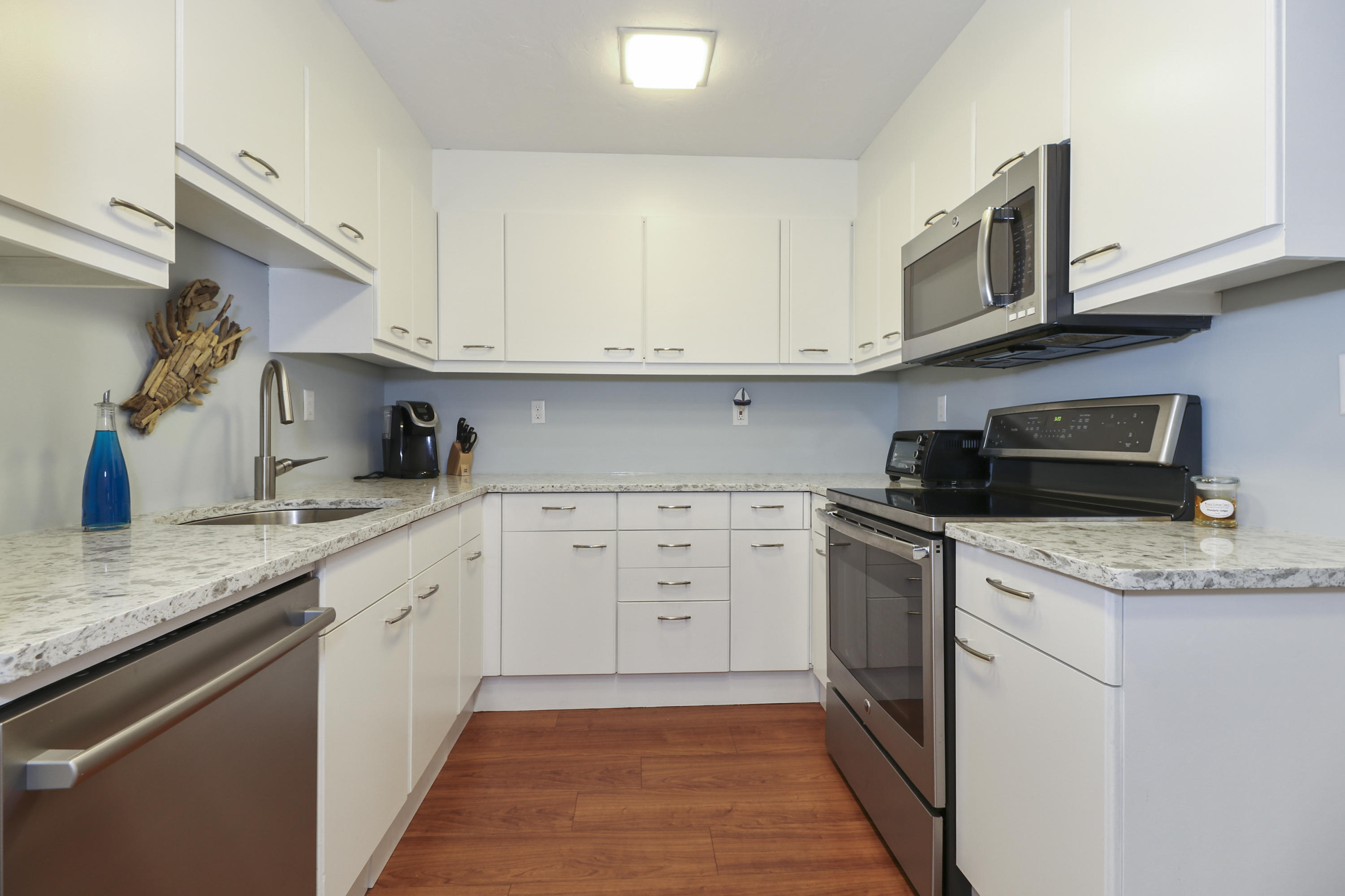 727 Main Street, Unit E1 Osterville, MA 02655 - Photo 10 of 20 a kitchen with stainless steel appliances granite countertop a sink and dishwasher a stove top oven with white cabinets