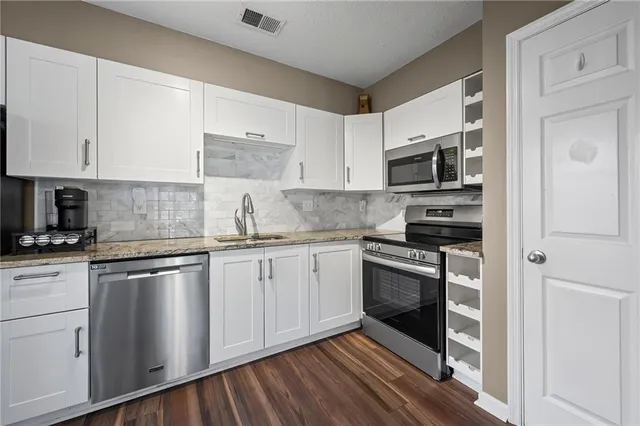 a kitchen with stainless steel appliances granite countertop a stove and white cabinets