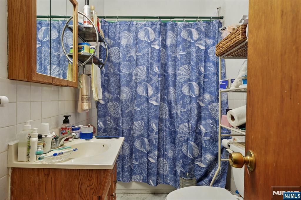 75 Coolidge Street Irvington, NJ 07111 - Photo 16 of 30 a bathroom with a sink a toilet and shower curtain