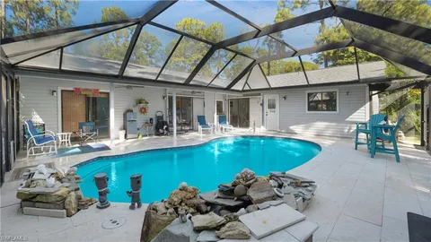 a view of a swimming pool with a dining table and chairs under an umbrella