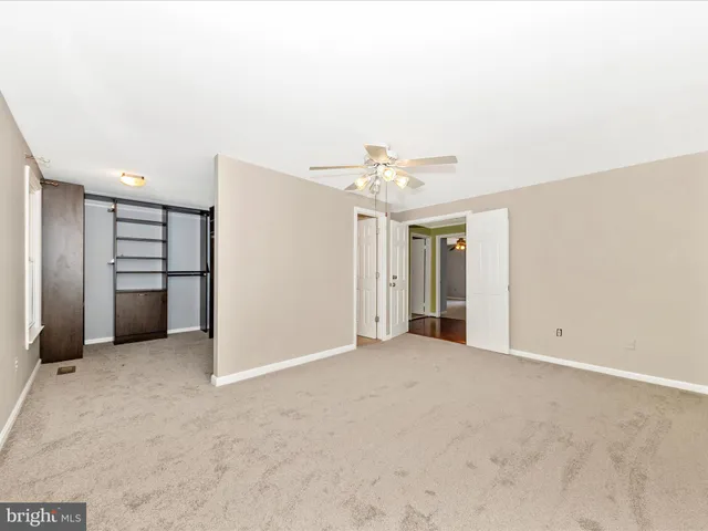 an empty room with a chandelier fan and windows