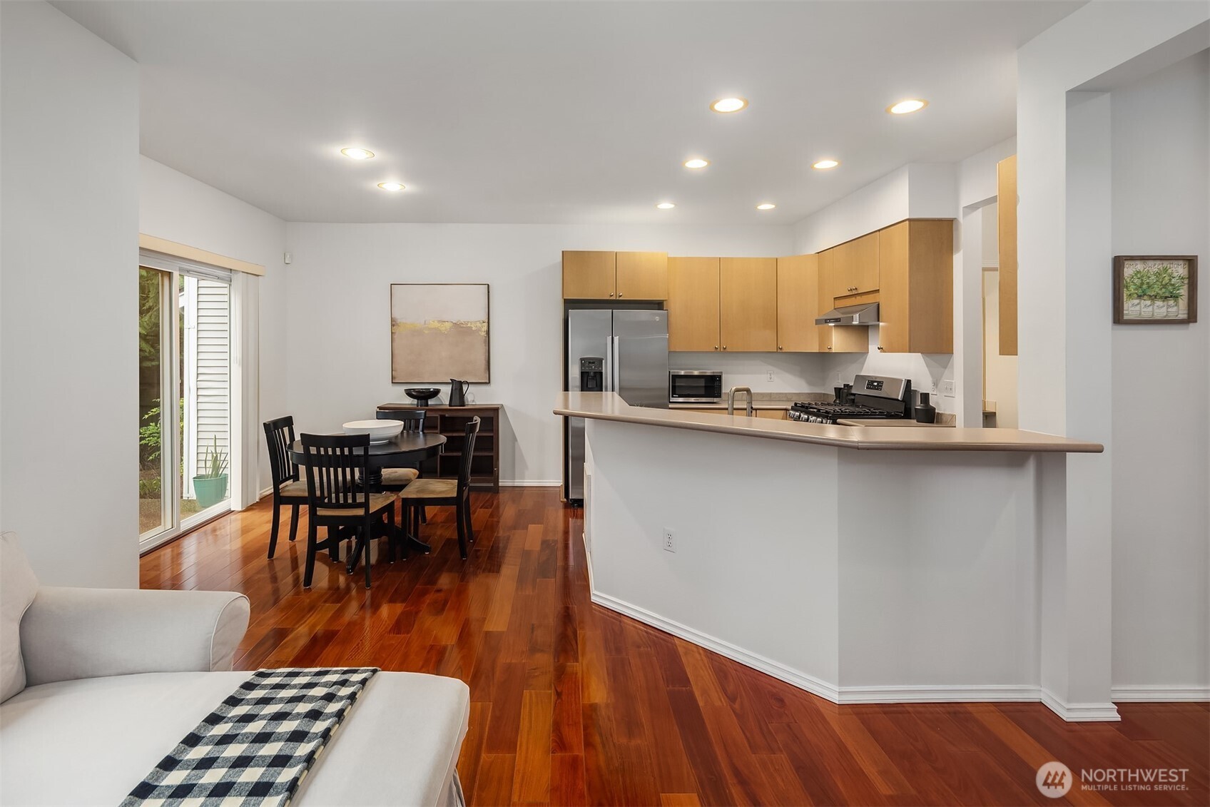 325 South 51st Street, Unit A Renton, WA 98055 - Photo 13 of 39 a kitchen with stainless steel appliances granite countertop a stove a sink a microwave a dining table and chairs with wooden floor