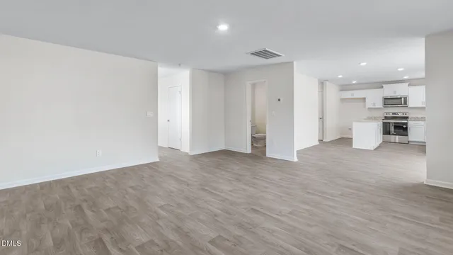 a view of a big room with wooden floor and windows