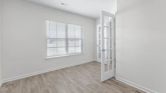 a view of an empty room with wooden floor and a window