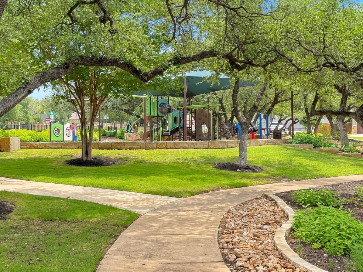 4105 Haight Street Round Rock, TX 78681 - Photo 39 of 40 Manicured greenspace featuring a winding concrete pathway, mature shade trees, a rock garden border, and a visible playground structure