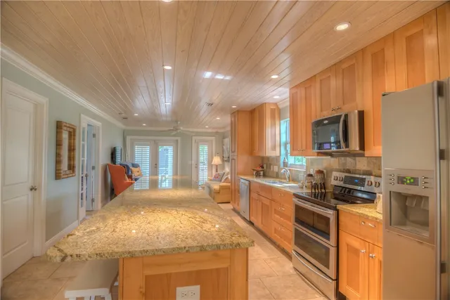 a large kitchen with kitchen island a large counter top space a sink stainless steel appliances and cabinets