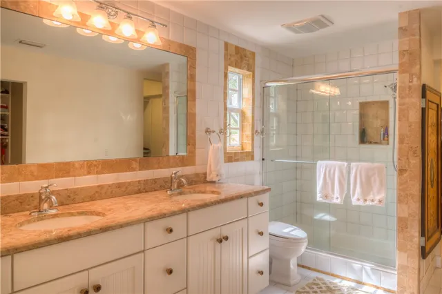 a bathroom with a granite countertop sink a toilet a mirror and shower