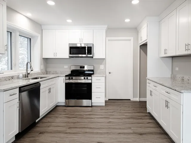 a kitchen with stainless steel appliances granite countertop a stove top oven a sink and a refrigerator