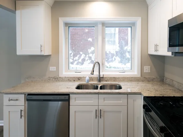 a kitchen with granite countertop kitchen island a sink appliances and a window