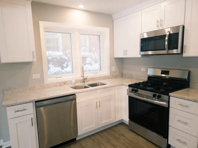 a kitchen with stainless steel appliances a sink a stove a microwave and cabinets