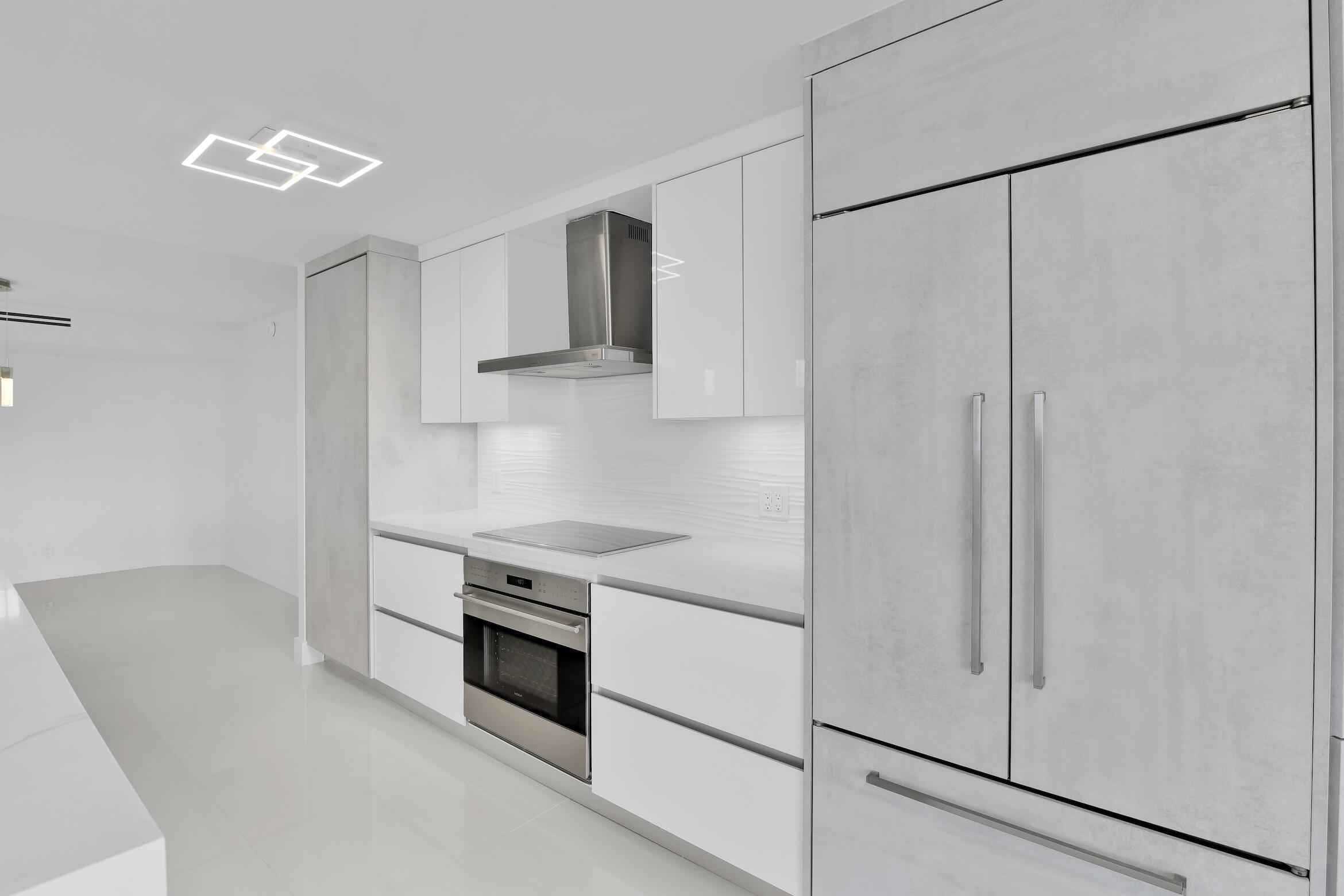 550 South Ocean Boulevard, Unit 403 Boca Raton, FL 33432 - Photo 9 of 55 a kitchen with stainless steel appliances white cabinets and wooden floors