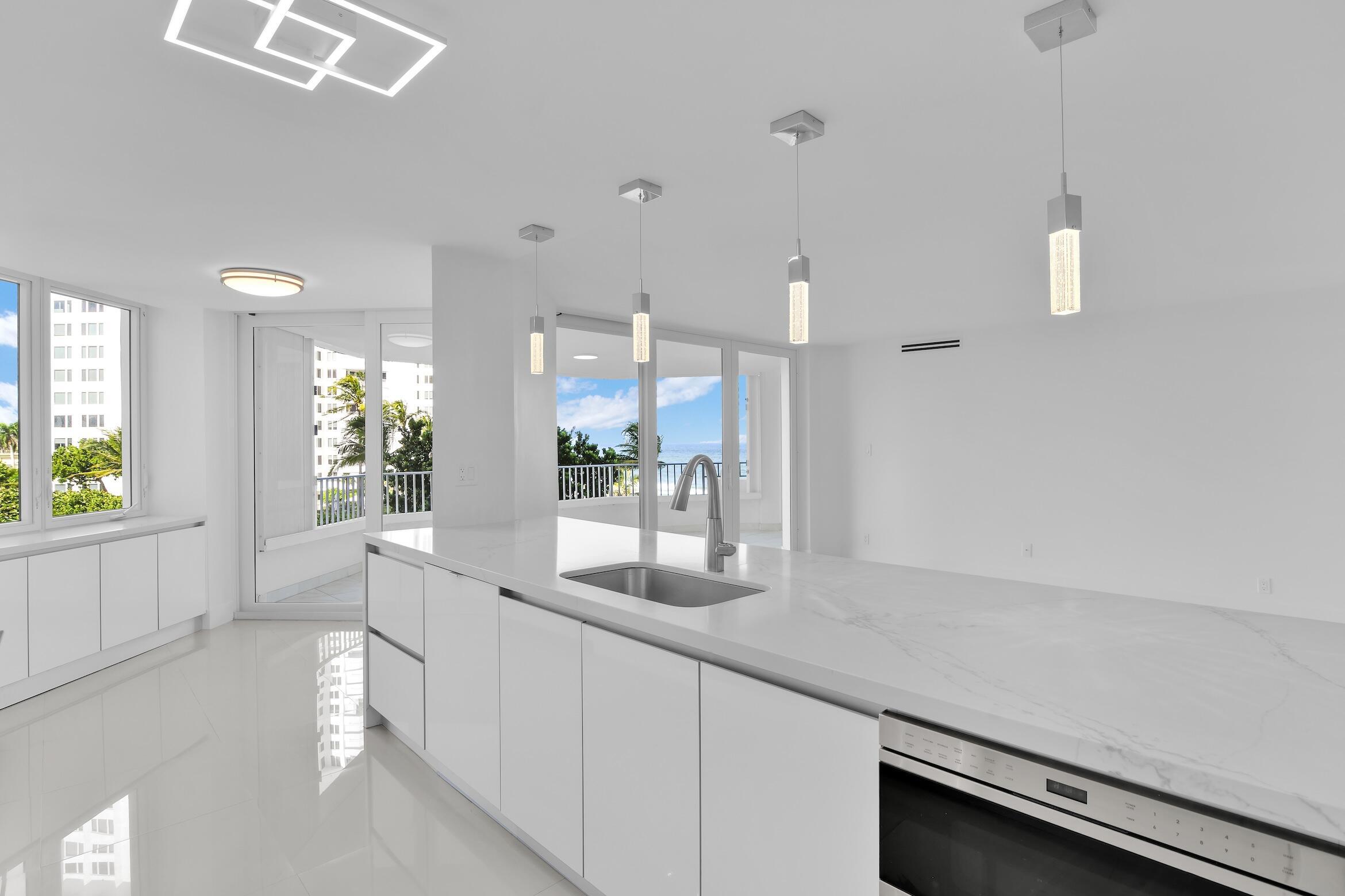 550 South Ocean Boulevard, Unit 403 Boca Raton, FL 33432 - Photo 10 of 55 a large white kitchen with a large window and stainless steel appliances