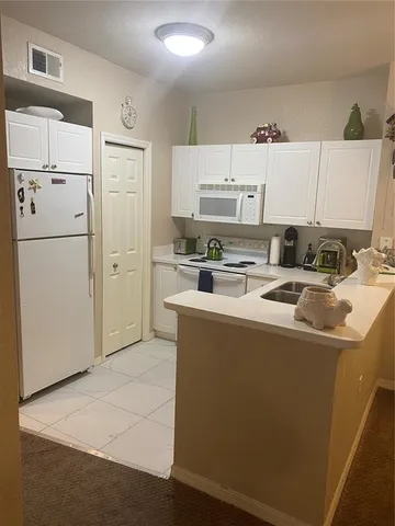 a kitchen with stainless steel appliances a refrigerator a stove a sink and white cabinets