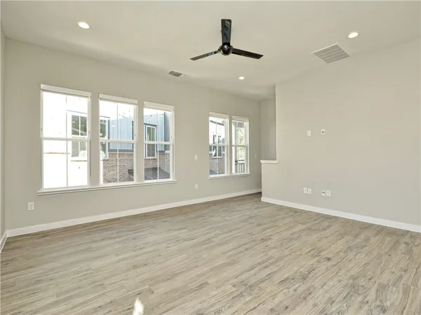 an empty room with wooden floor and windows