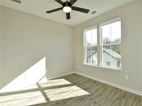 an empty room with wooden floor cabinet and windows