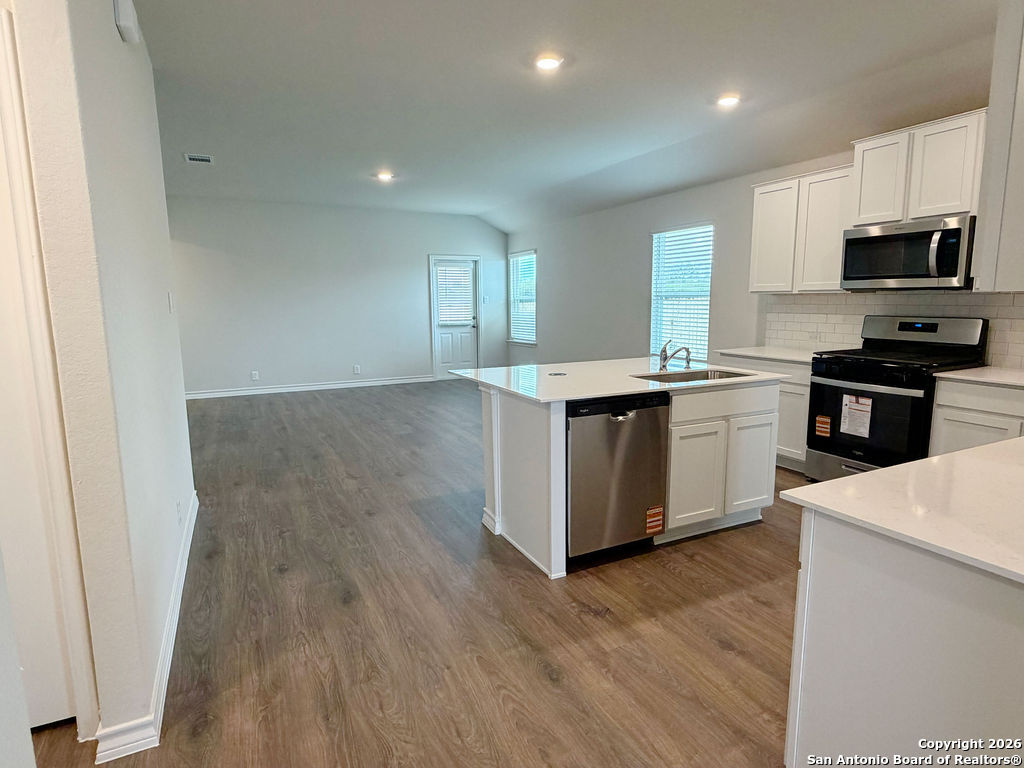 607 Fluted Cibolo, TX 78108 - Photo 16 of 50 a kitchen with stainless steel appliances granite countertop a stove top oven a sink dishwasher and a refrigerator with wooden floor