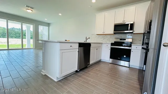 a kitchen with stainless steel appliances granite countertop a stove a sink and a microwave