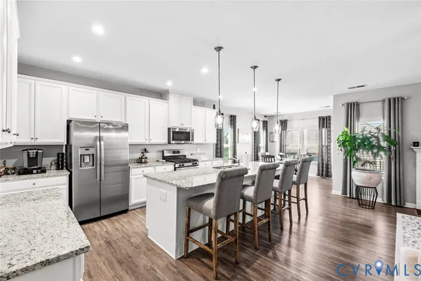 a kitchen with stainless steel appliances a dining table chairs stove refrigerator and microwave