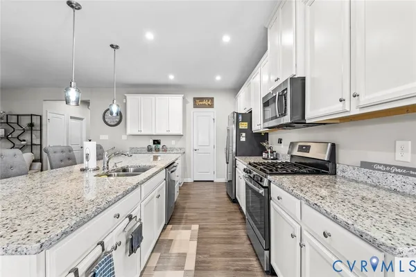 a large kitchen with stainless steel appliances granite countertop a stove top oven a sink dishwasher and a wooden cabinets