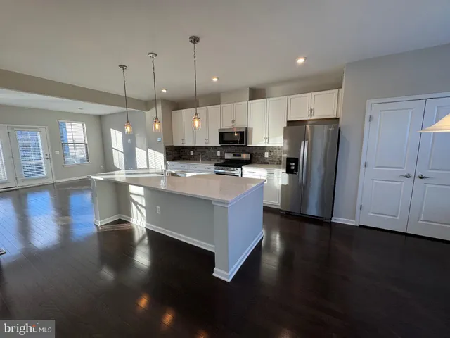 a kitchen with stainless steel appliances granite countertop a refrigerator a stove a sink dishwasher and a oven with wooden floor